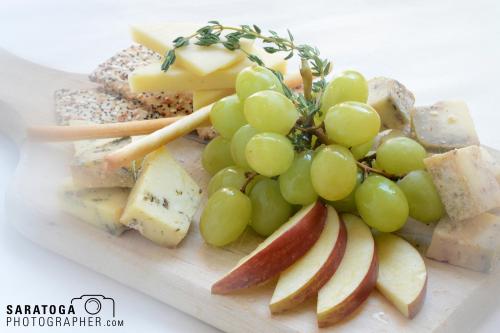 Soft focus view of cheese platter with grapes and stylized apple with crackers